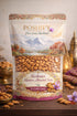 Kashmiri Mamra almonds pack with picturesque mountain background, showcasing 1kg of nutritious nuts.